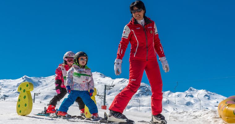 Deux enfants sur les skis avec leur moniteur