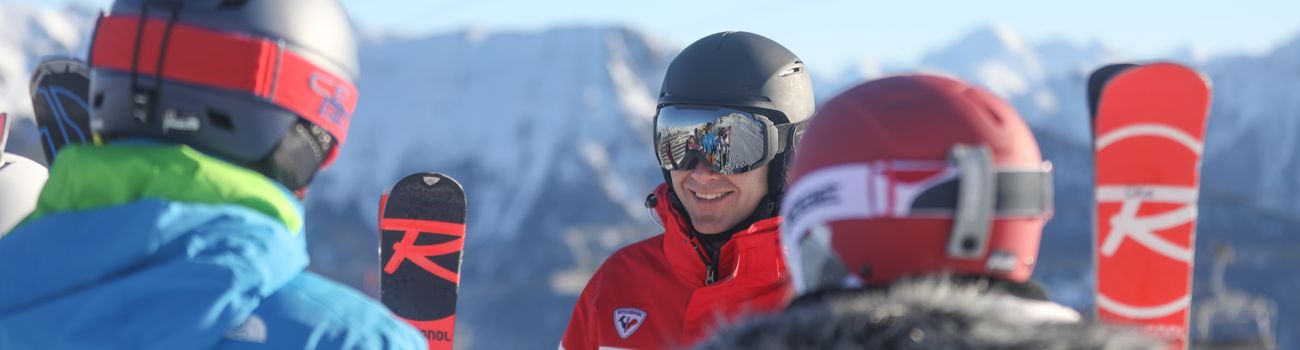 Adolescents et moniteur ESF en face à face skis aux mains 